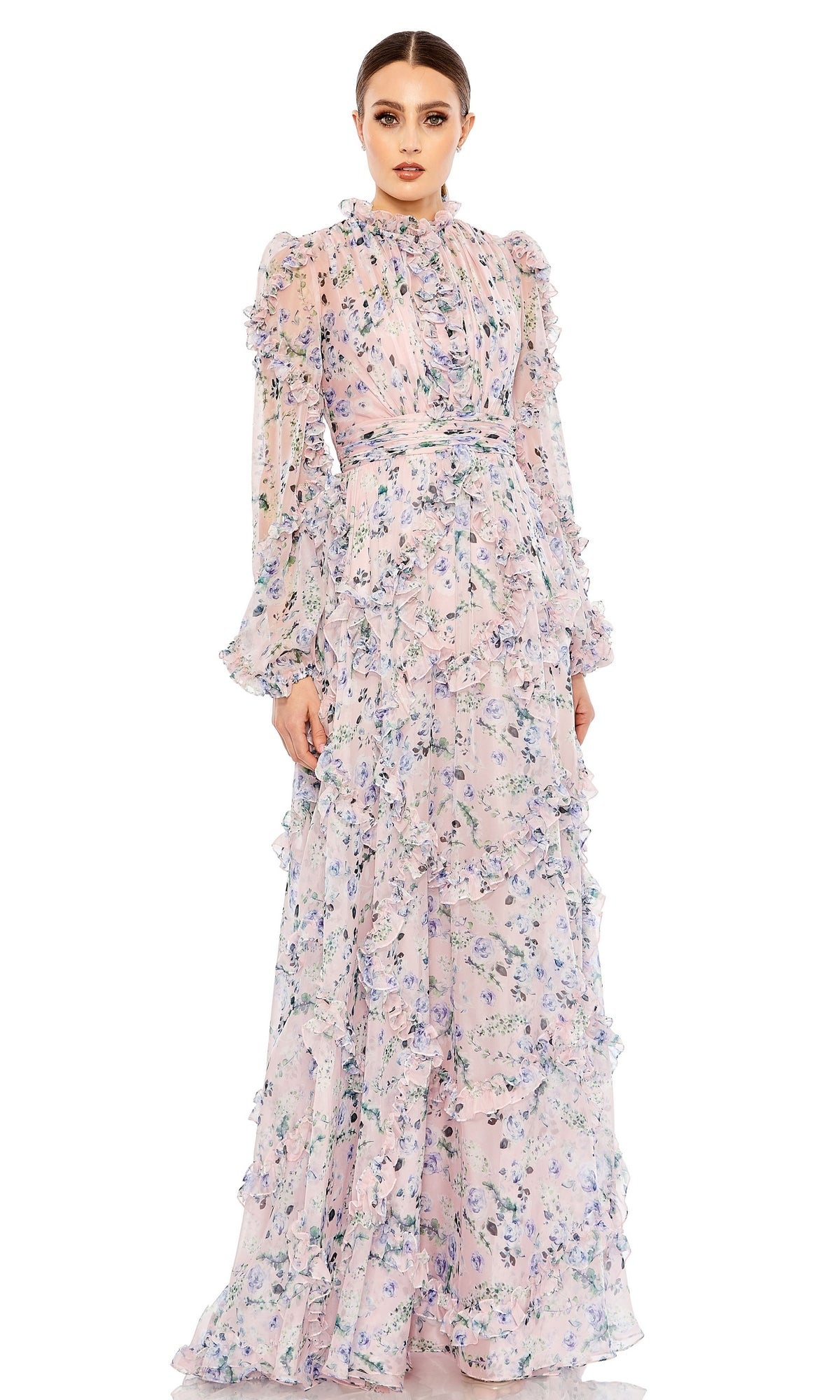 A woman models the Long Formal Dress 68232 by Mac Duggal—a blush gown with long sleeves, high neck, and a layered ruffle skirt—standing against a white background.